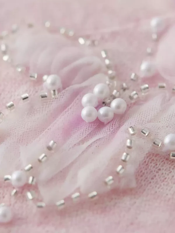 A light pink off-the-shoulder beaded knitted sweater